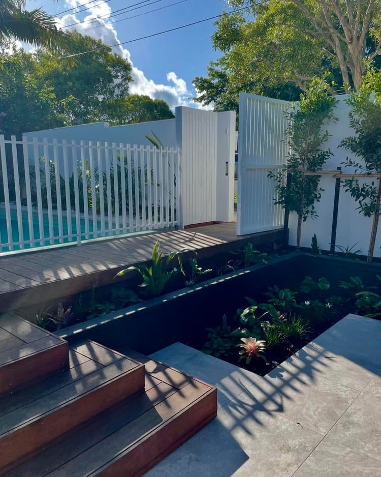 Pool surround with white fence and timber deck by Jones Projects